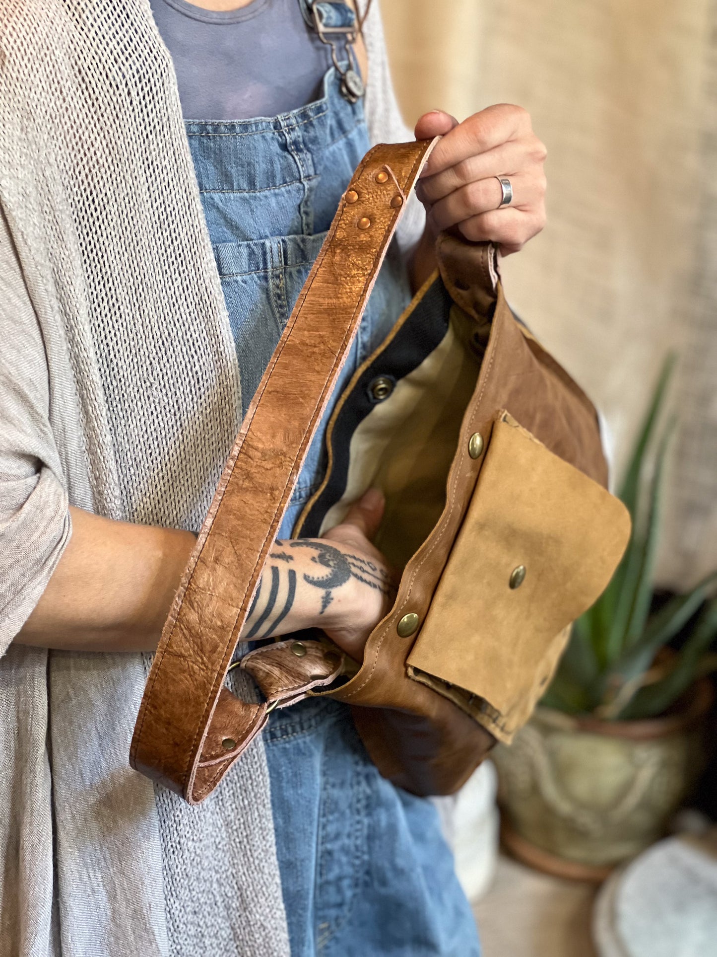 Person holding a brown leather bag with a neutral background