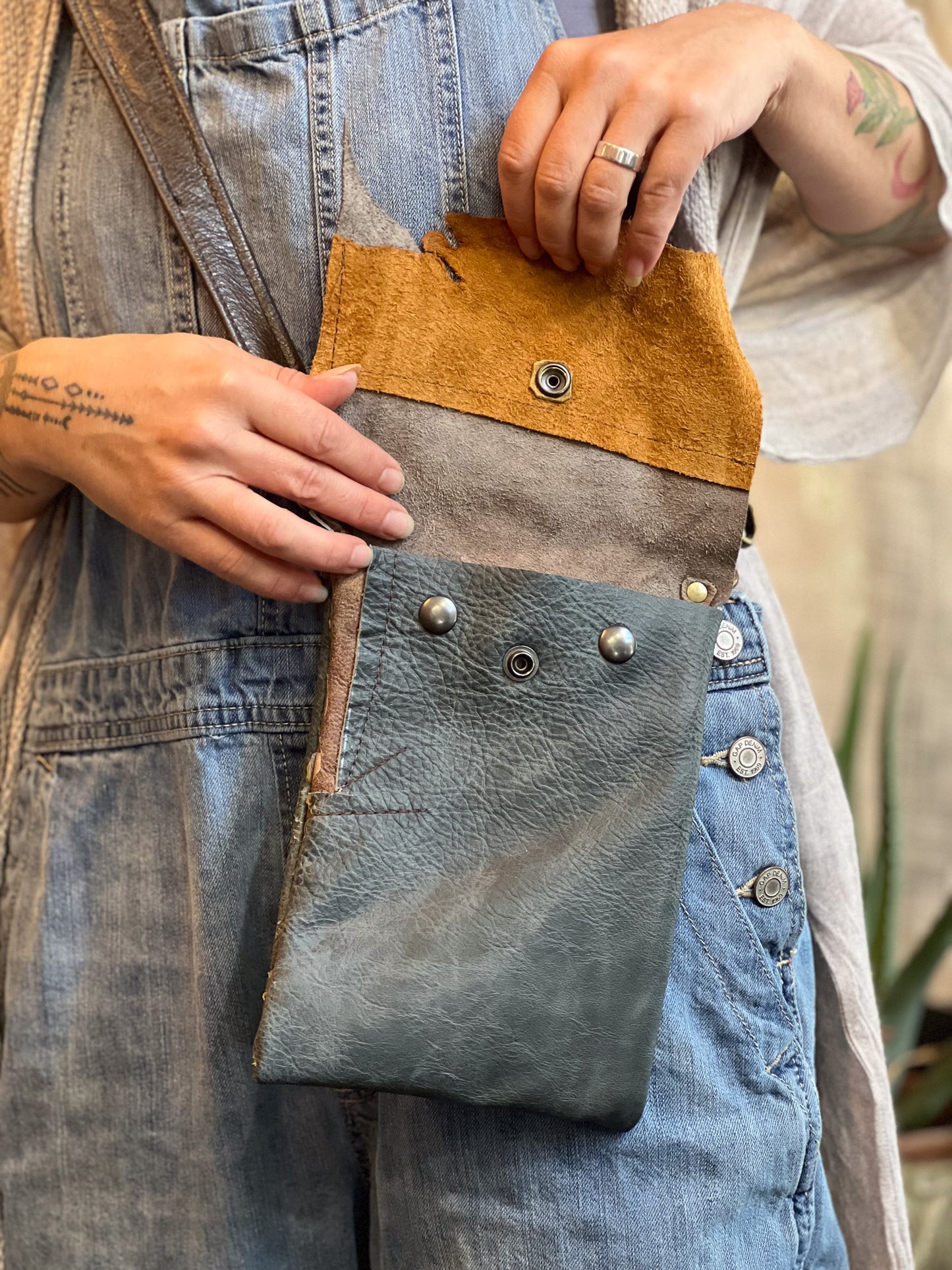 Person holding a blue and brown leather bag with visible stitching details.