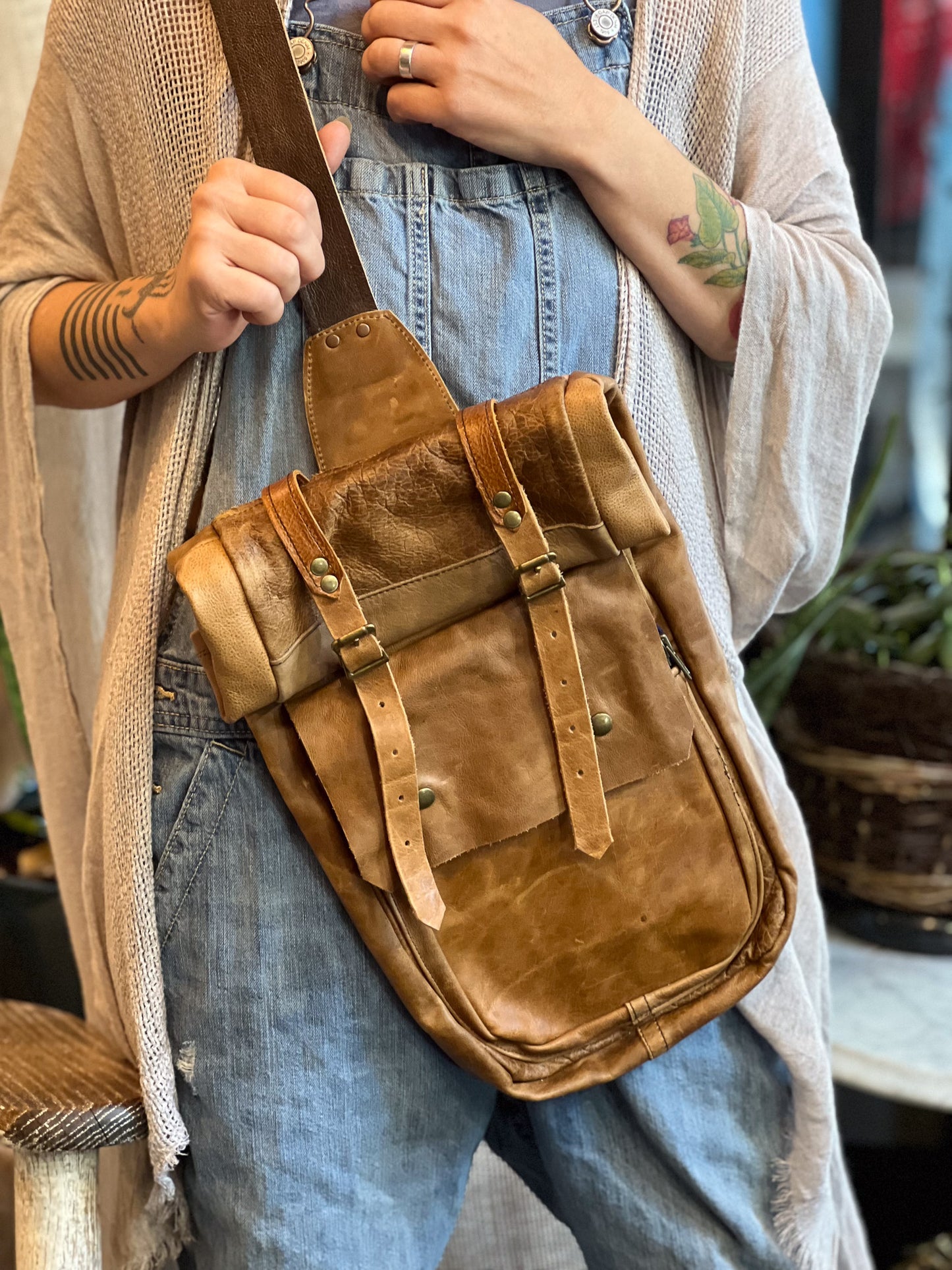 Person holding a brown leather bag with a neutral background