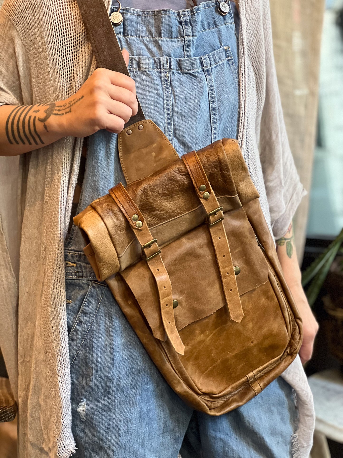 Person holding a brown leather bag with a neutral background