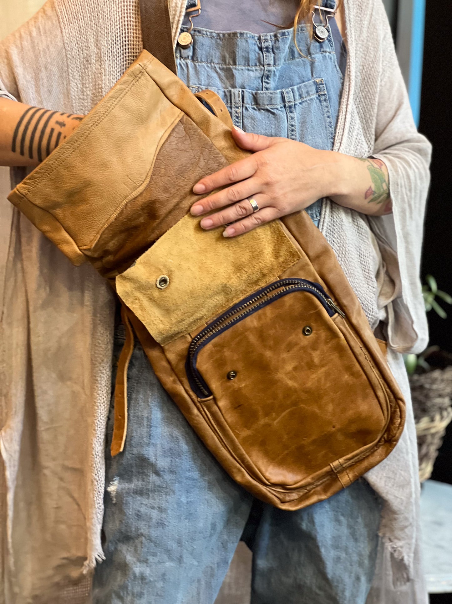 Person holding a brown leather bag with a neutral background