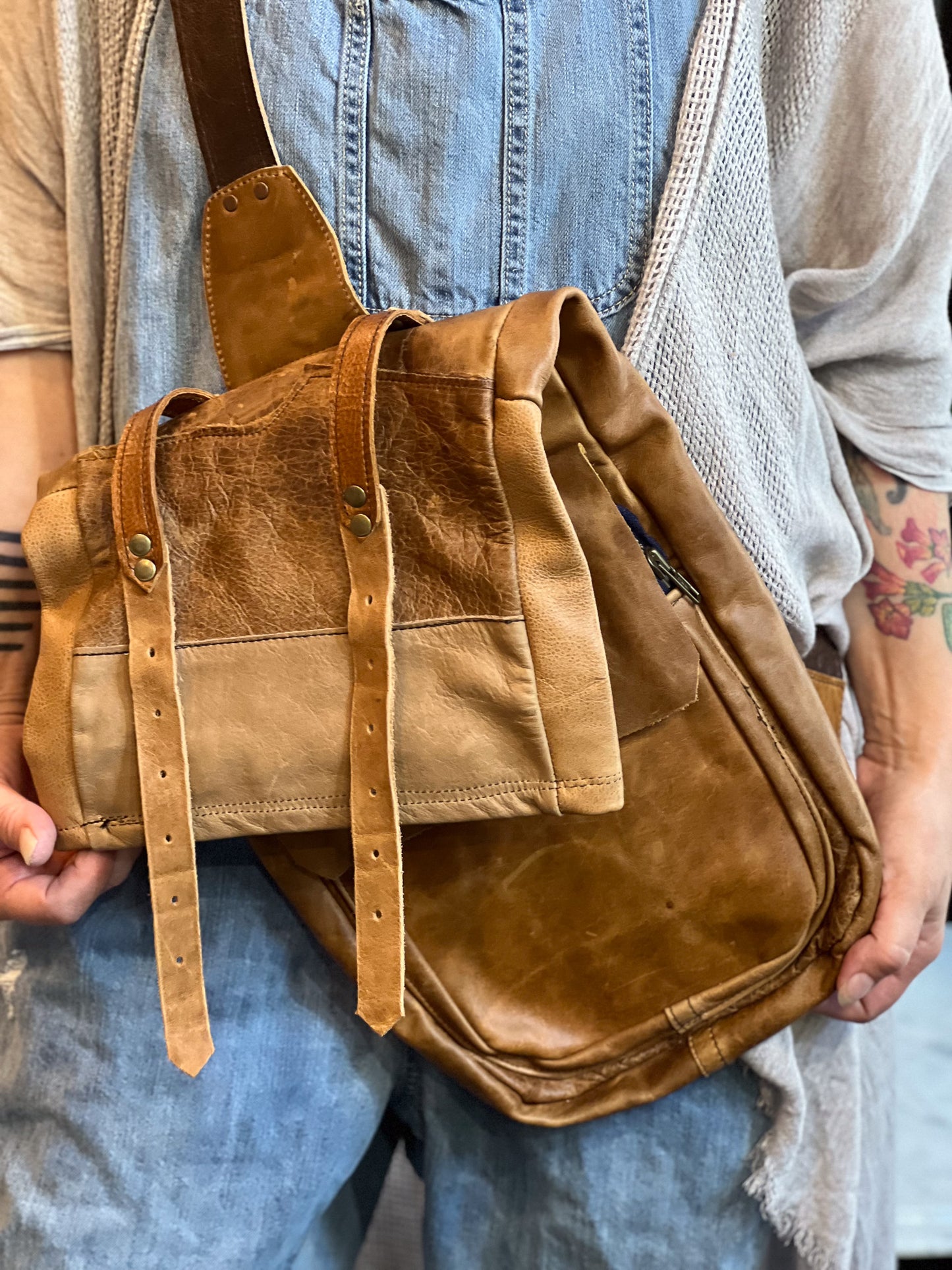 Brown leather bag held by a person wearing a denim apron.