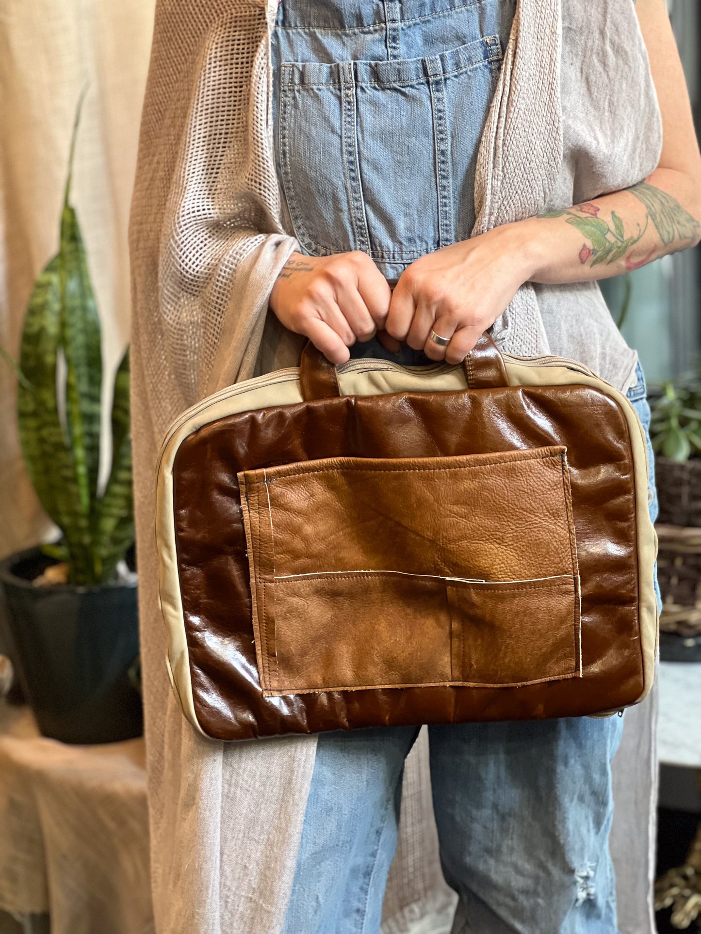 Person holding a brown leather bag with a neutral background