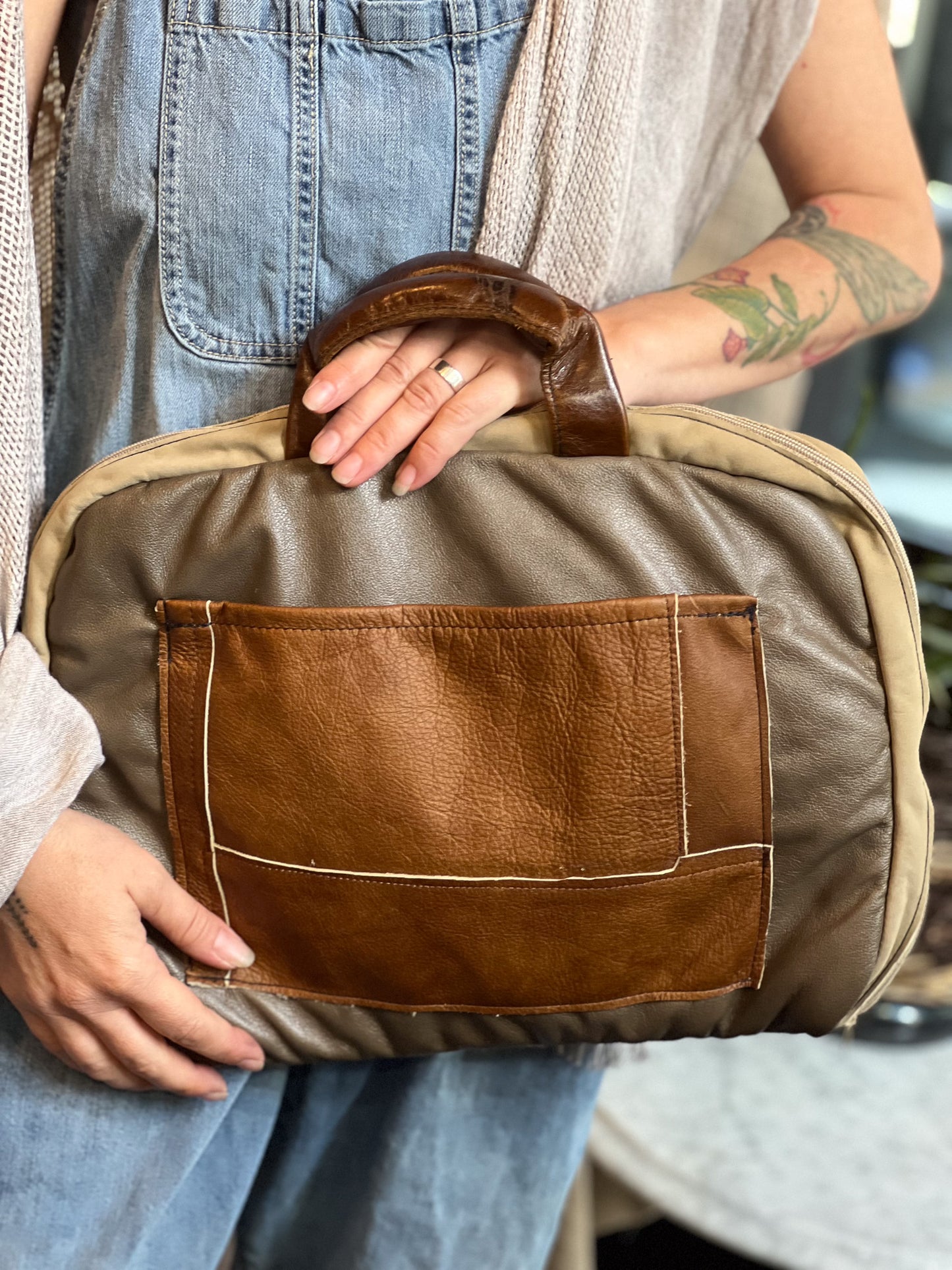 Person holding a brown leather bag with a neutral background