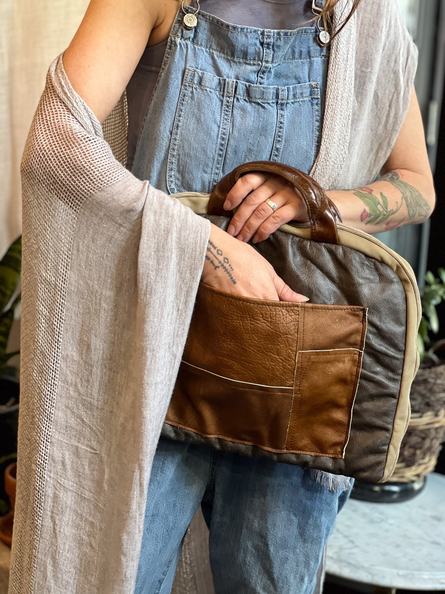 Person holding a brown leather bag with a neutral background