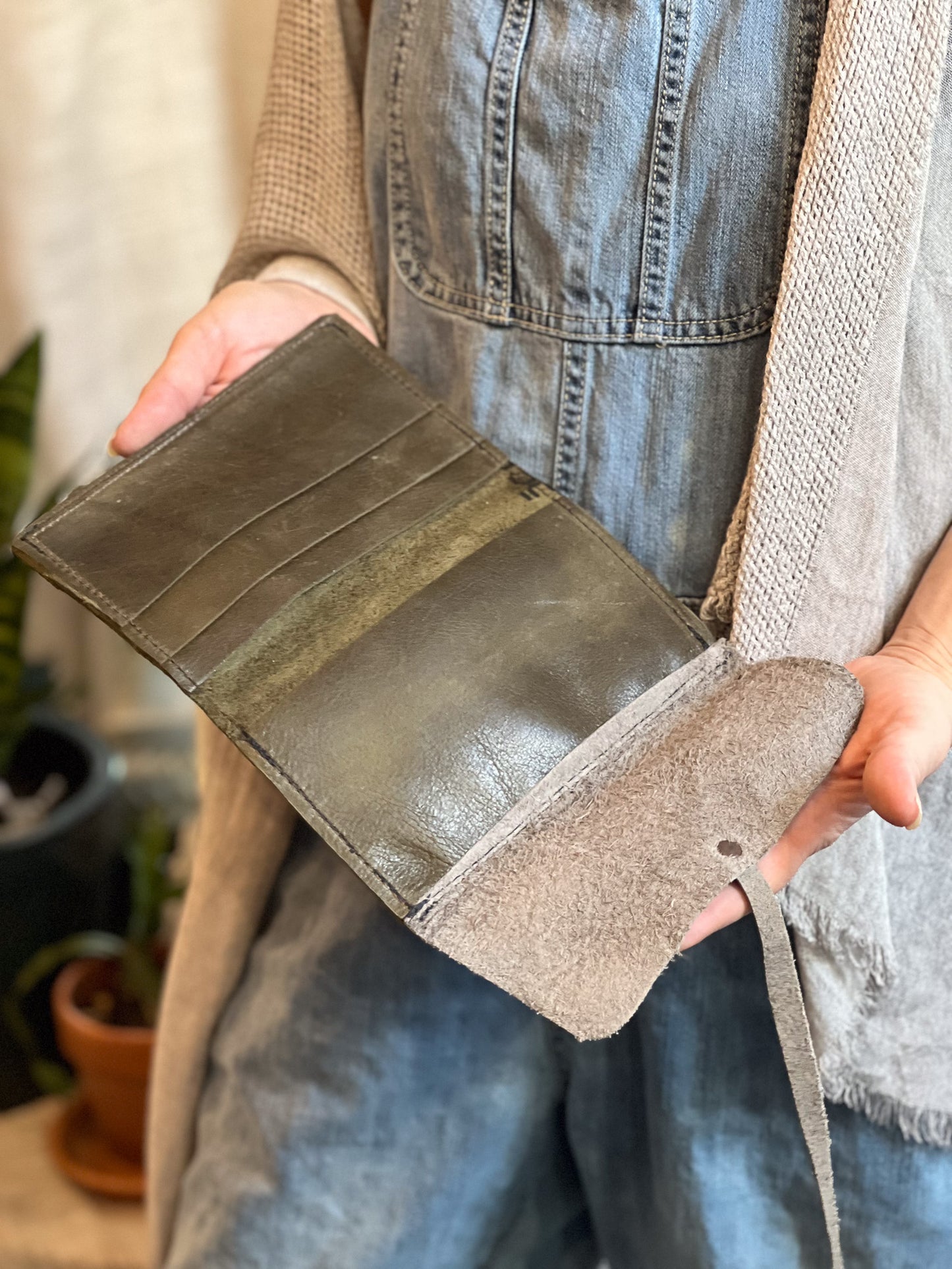 Person holding a brown leather wallet with a strap