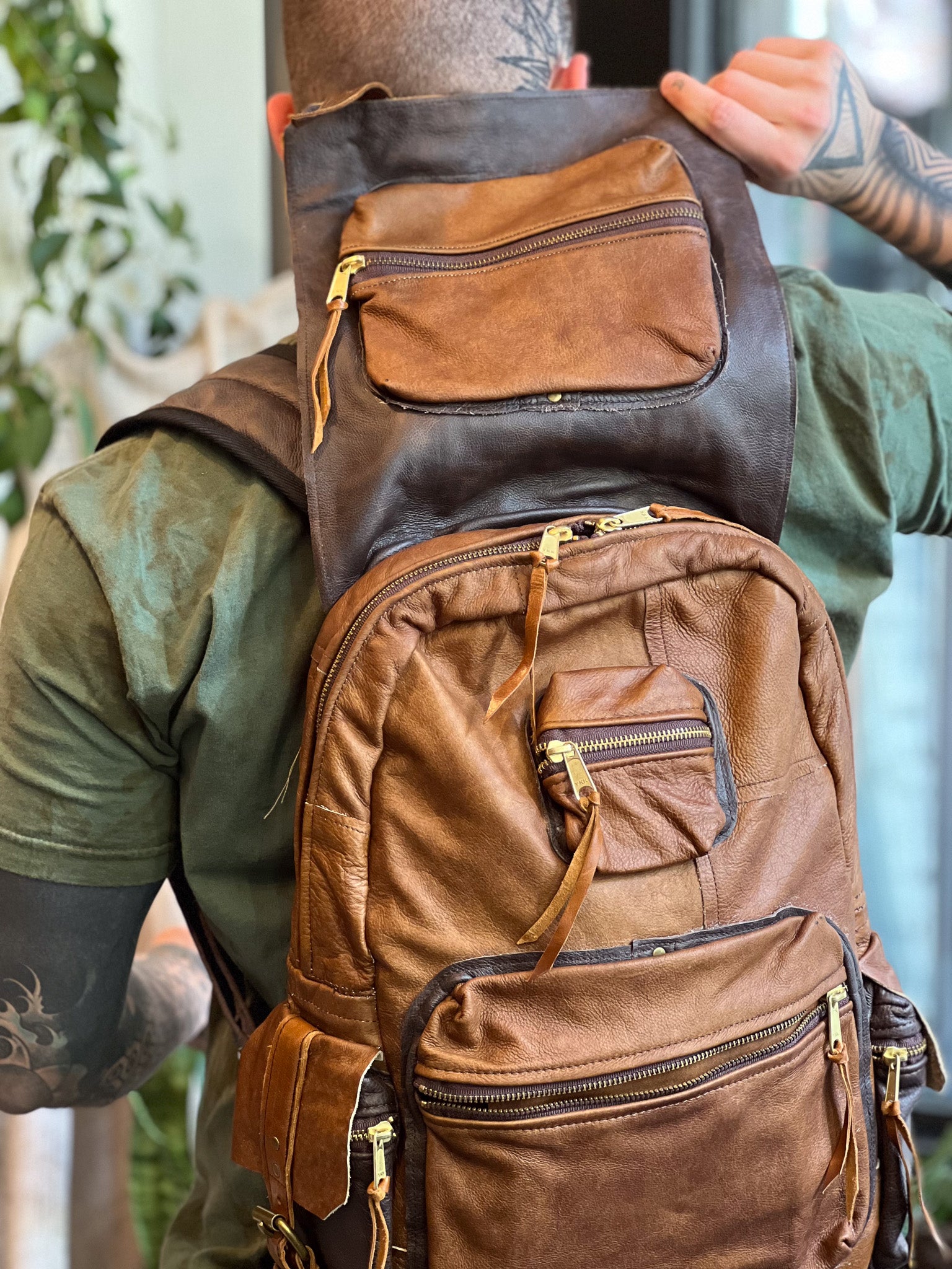 Brown leather backpack worn by a person with a blurred background