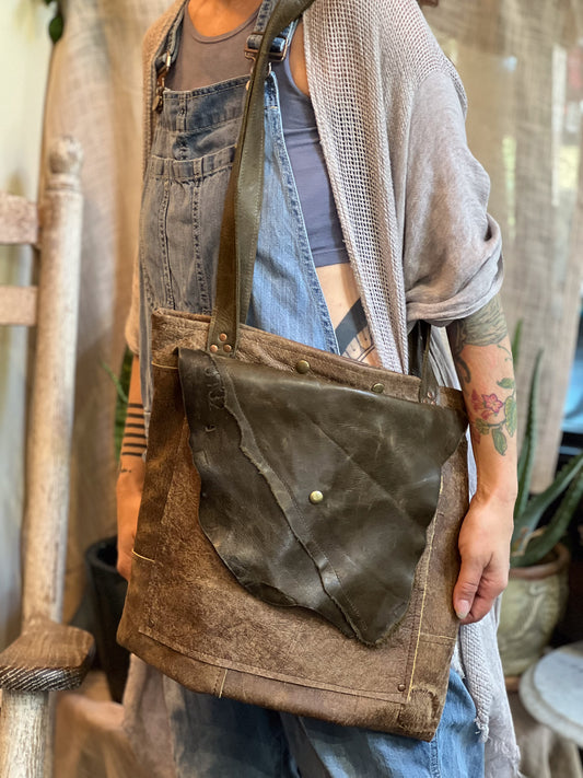 Person wearing a brown leather crossbody bag with a rustic background