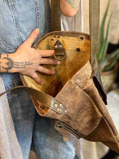 Person holding a brown leather bag with visible tattoos on hands