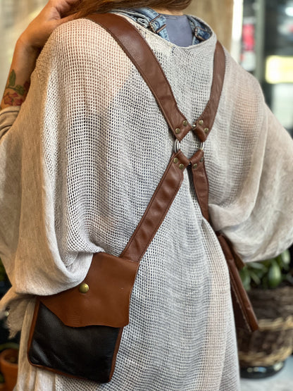 Person wearing a brown leather crossbody bag with a neutral background