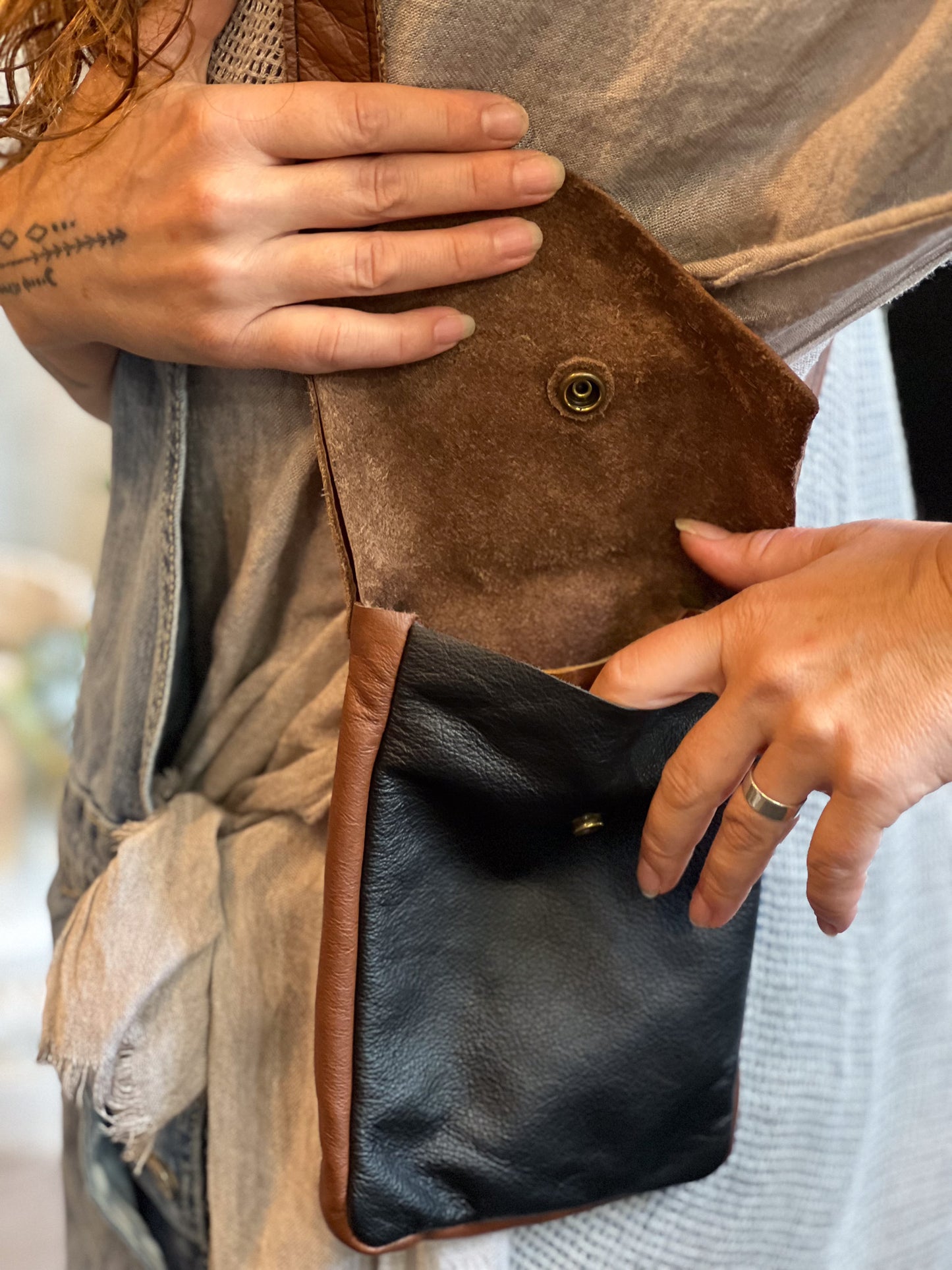 Close-up of a person holding a brown leather clutch bag.