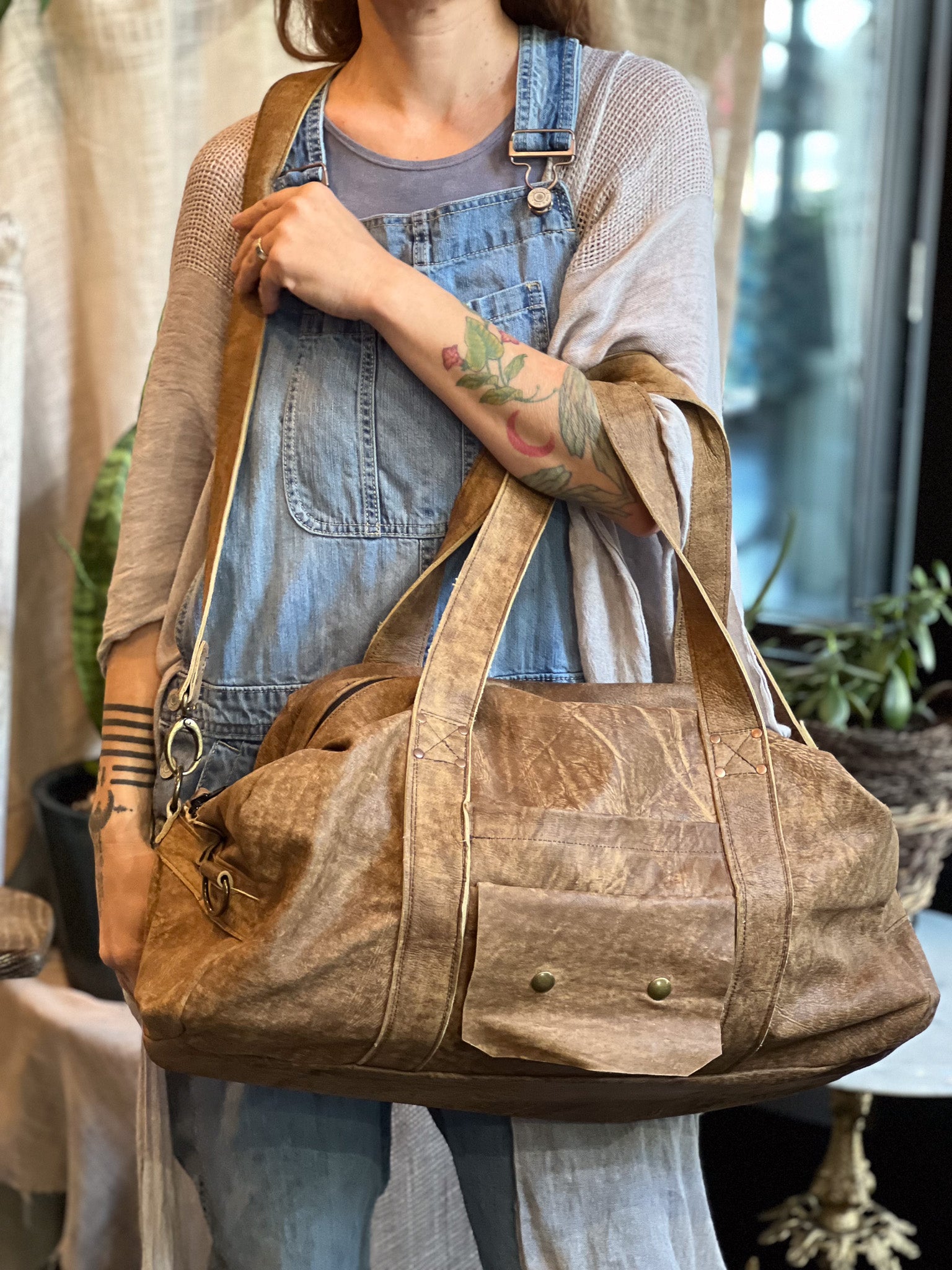 Person holding a brown leather bag with a blurred background