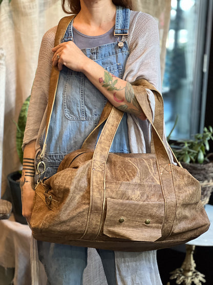 Person holding a brown leather bag with a blurred background