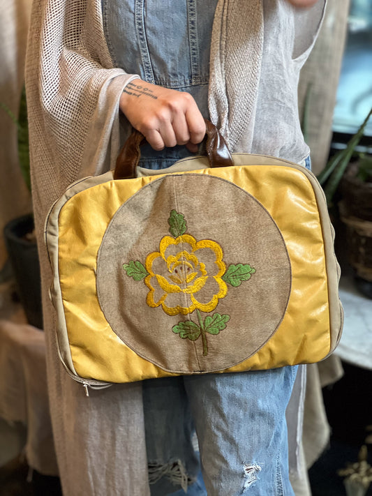 Person holding a yellow bag with floral embroidery