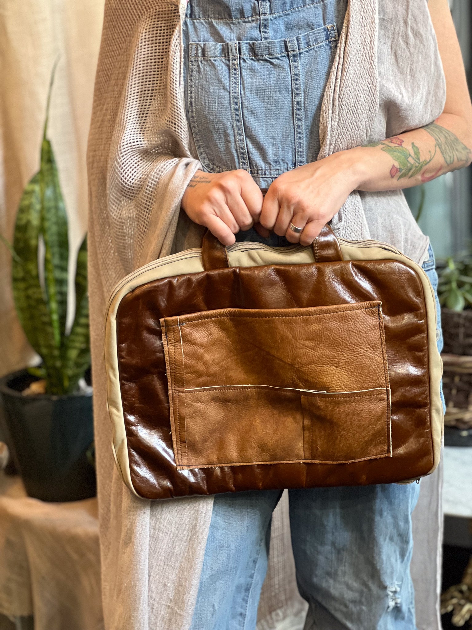 Person holding a brown leather bag with a neutral background