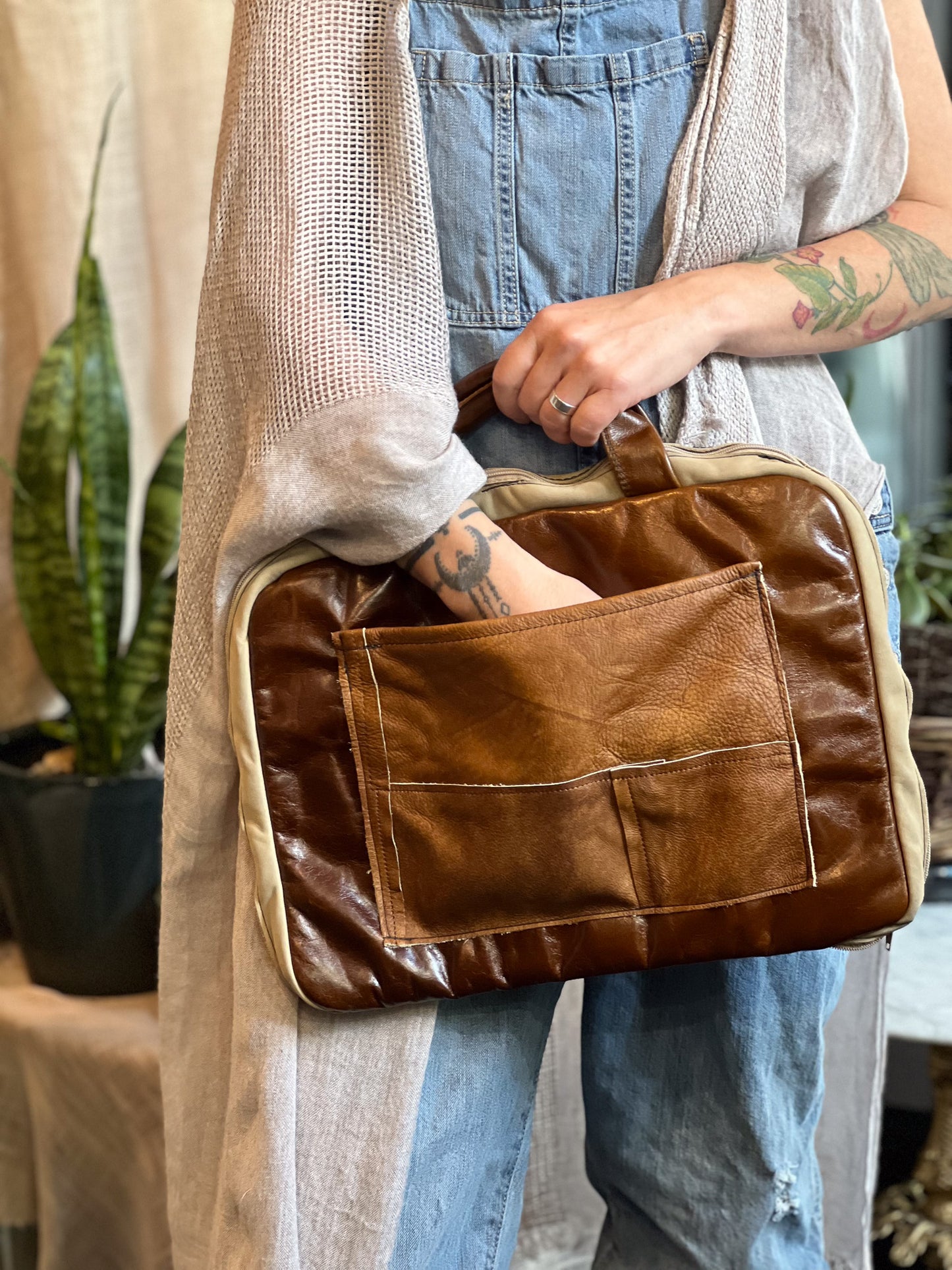 Person holding a brown leather bag with a neutral background