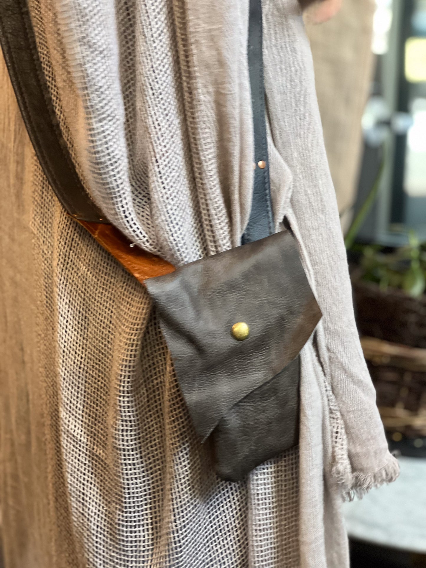 Person wearing a brown coat with a black leather pouch on a blurred background