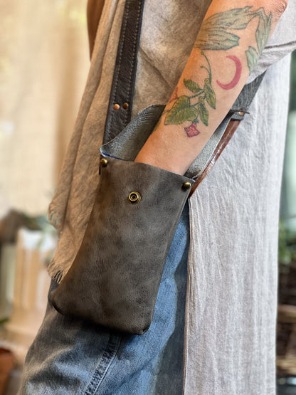 Person wearing a brown leather bag with visible tattoos on arm