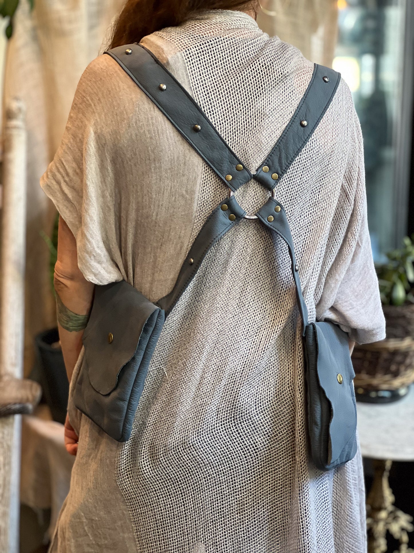 Person wearing a gray leather holster bag with straps over shoulders