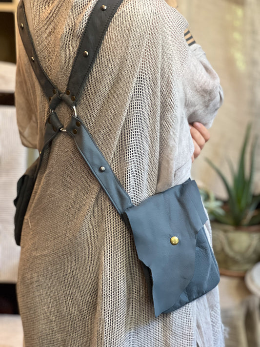 Person wearing a blue crossbody bag with a strap over shoulder, indoor setting