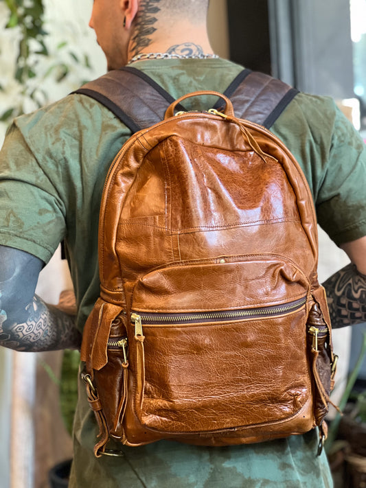 Person wearing a brown leather backpack with a blurred background