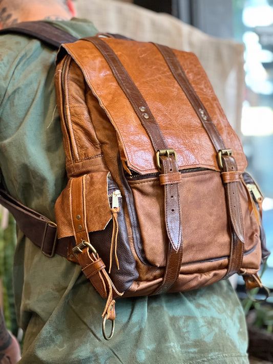 Brown leather backpack worn by a person, with a blurred background