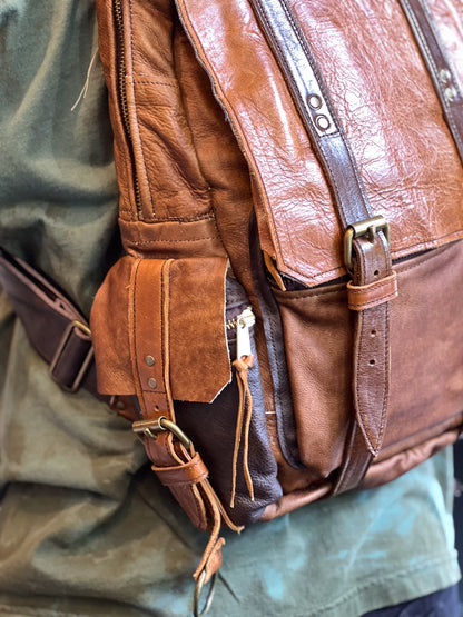 Brown leather backpack on a green fabric background