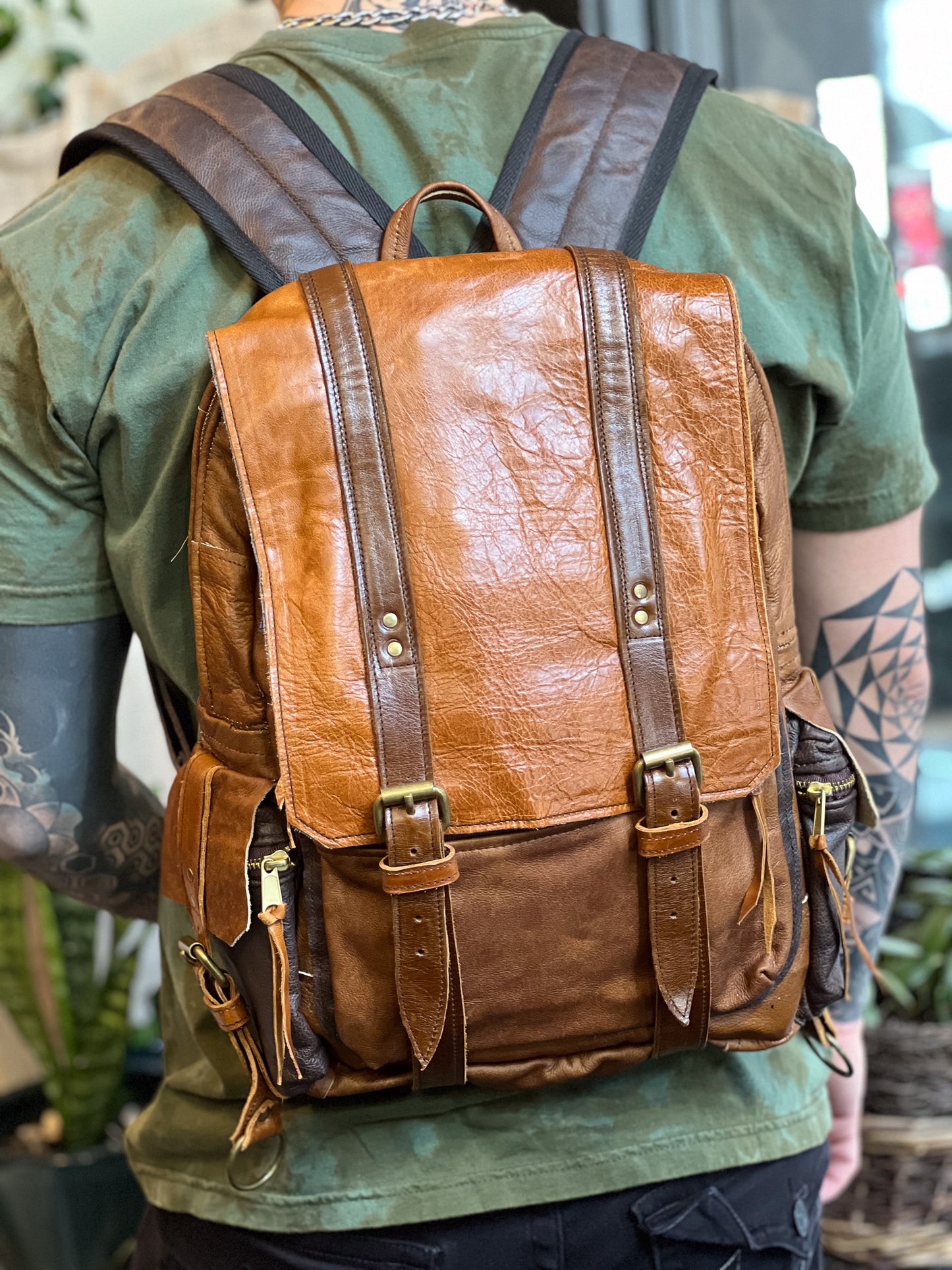 Person wearing a brown leather backpack with a green shirt.