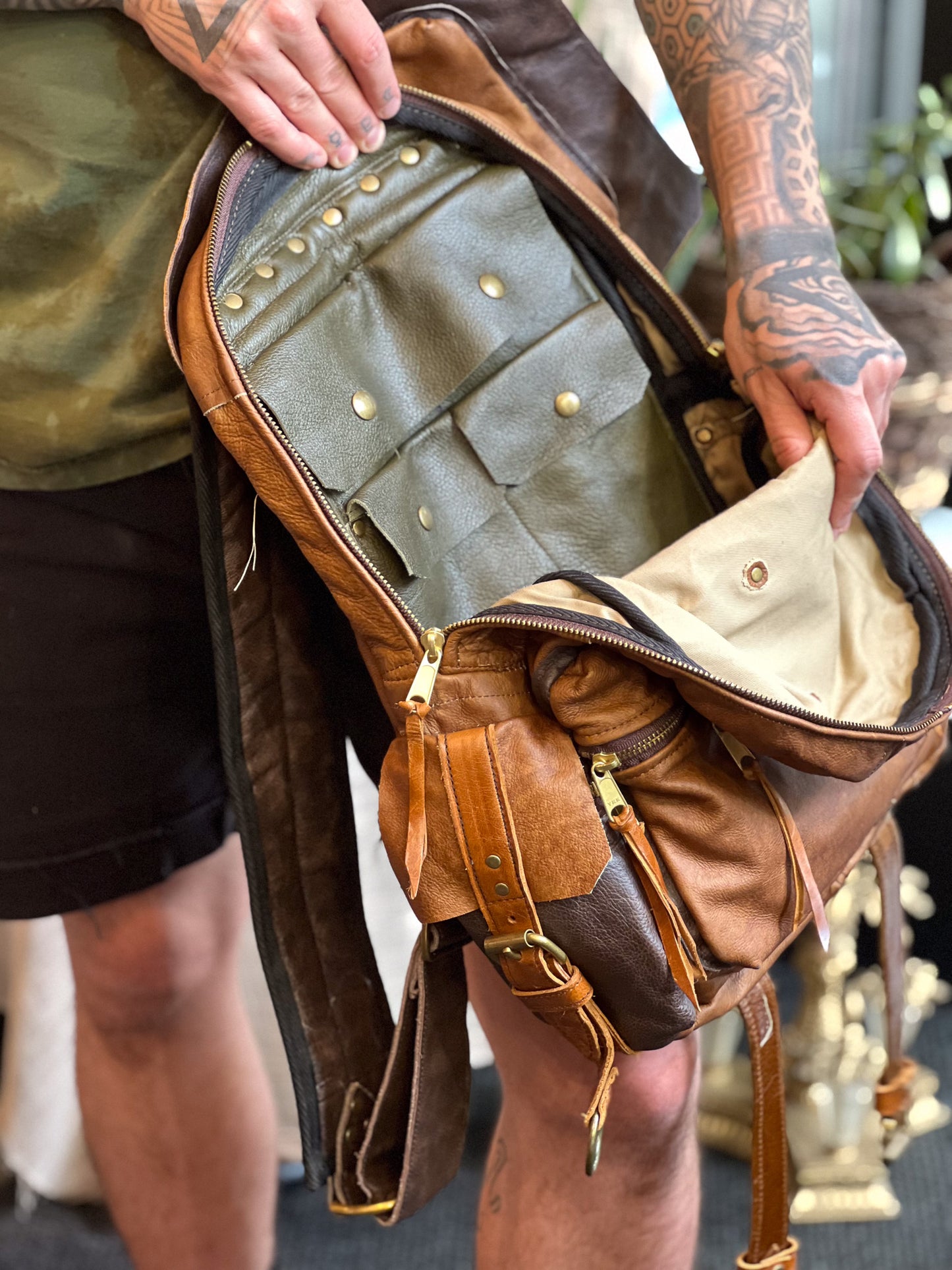 Person holding a brown leather bag with multiple compartments.