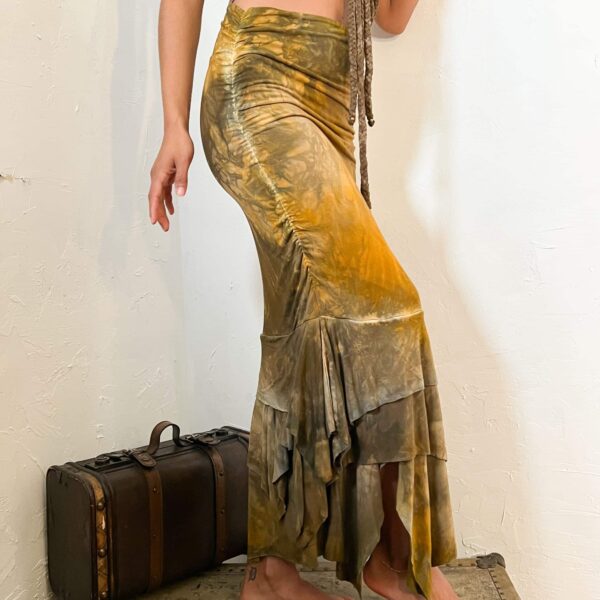 A women model showcasing a form-fitted, maxi pencil skirt, that flares at the bottom with a fishtail. The skirt has been dyed a marbling color of yellow, green & brown tones.