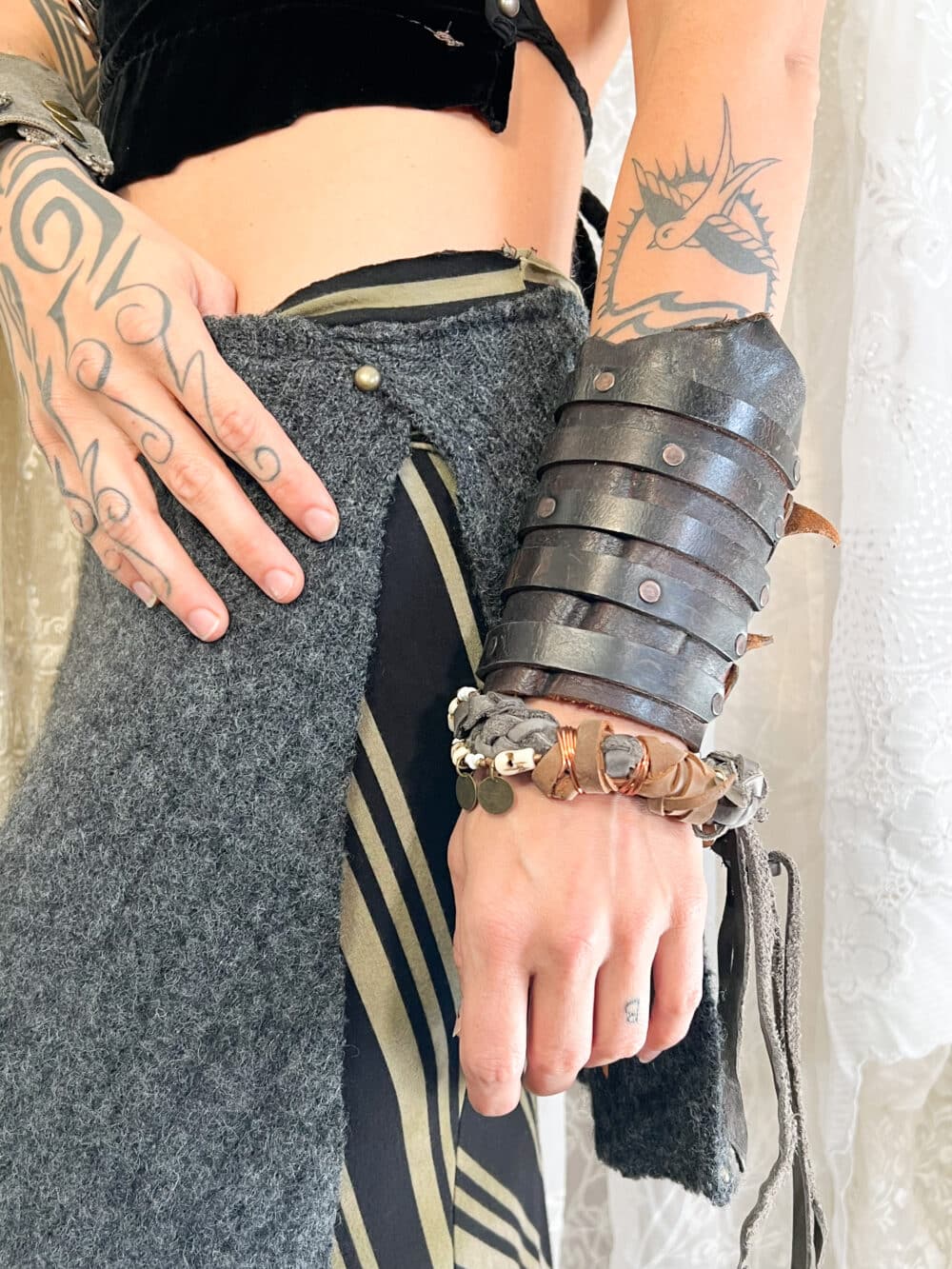 A thick brown leather arm gauntlet that covers the majority of a fore arm. Five leather stripes create the accents and are attached by rivets.