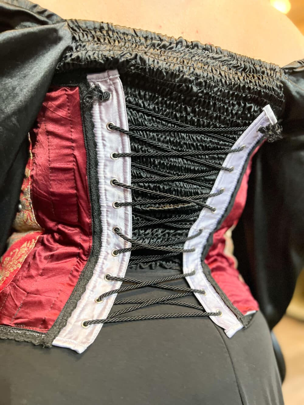 A Crimson textile renaissance bustier with paisley accents & black lace trim. Black Chord is the corset in back that helps cinch.